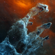 Tendrils of gas and dust look pale blue, against a backdrop of cooler orange gas.